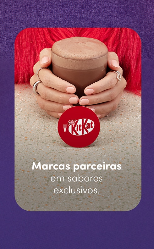 Descubra sabores exclusivos de marcas parceiras Nescafé Dolce Gusto como KitKat Banner de marcas parceiras da Nescafé Dolce Gusto com uma pessoa segurando uma xícara de bebida e o logotipo KitKat. Texto: “Marcas parceiras em sabores exclusivos